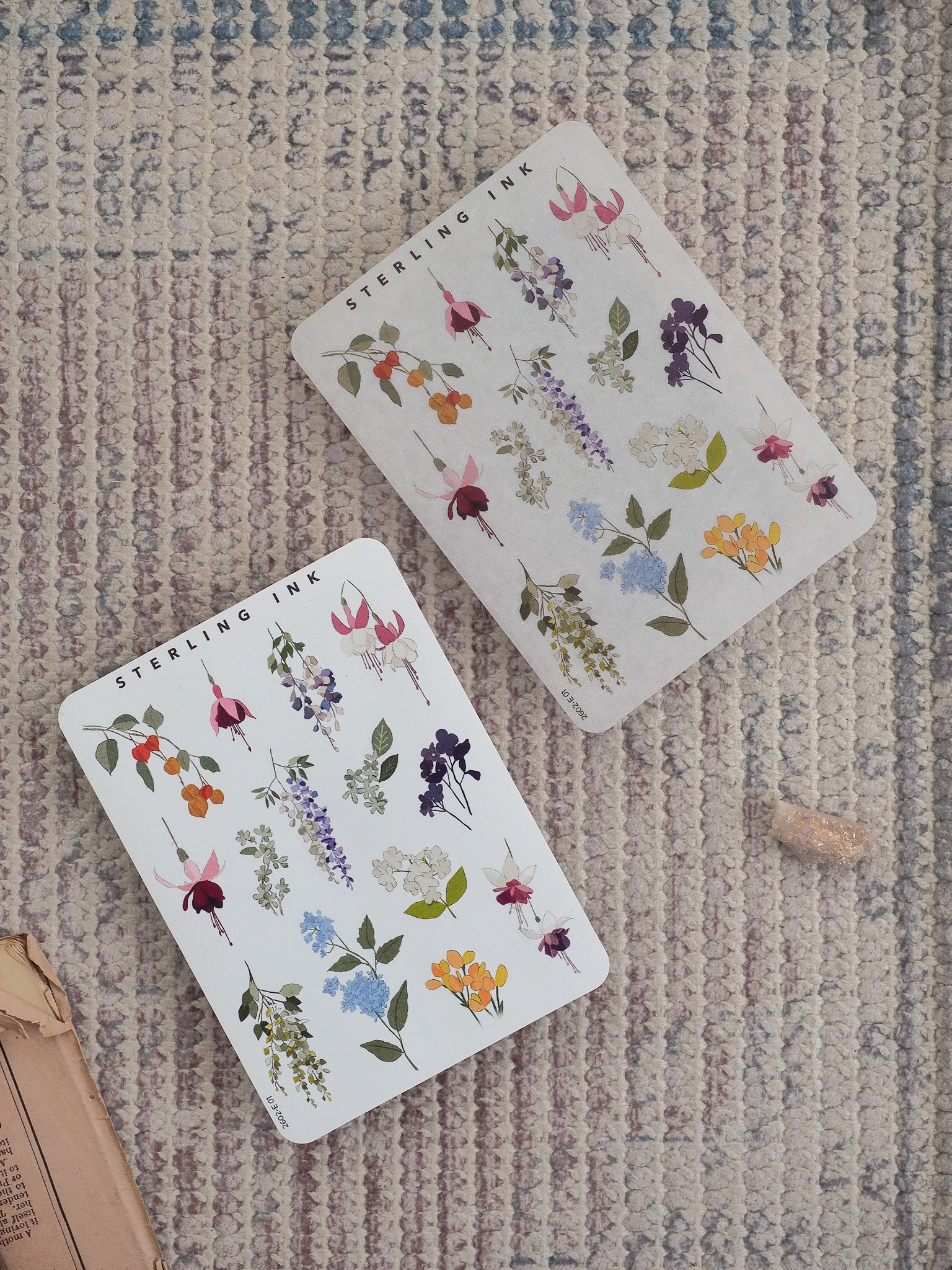 Delicate sticker sheets featuring a vibrant watercolor arrangement of spring blossoms, including lavender, cobalt blue, yellow, and blush pink floral elements.