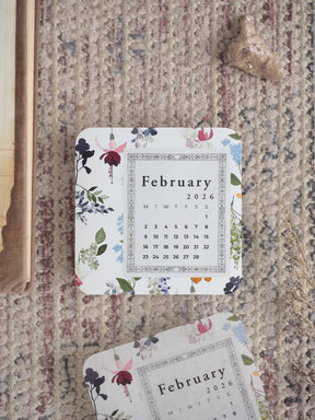 Elegant printable calendar page for February 2026, adorned with delicate watercolor floral bouquets featuring blush pink, deep blue, and sage green accents.