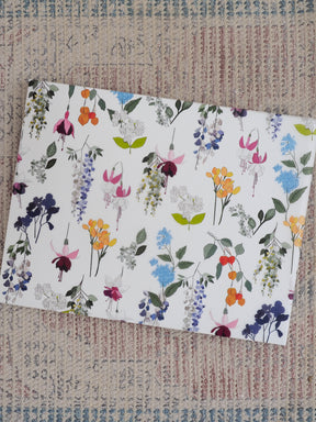 Vibrant watercolor floral pattern covering a planner, featuring abundant spring blossoms and greenery in delicate shades of lavender, blue, yellow, orange, and purple.