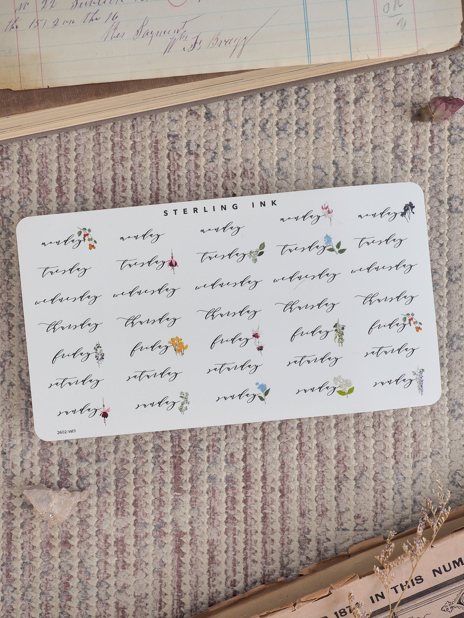 A delicate, white sticker sheet designed for planners, featuring seven days of the week each adorned with small, hand-drawn botanical accents and floral motifs.