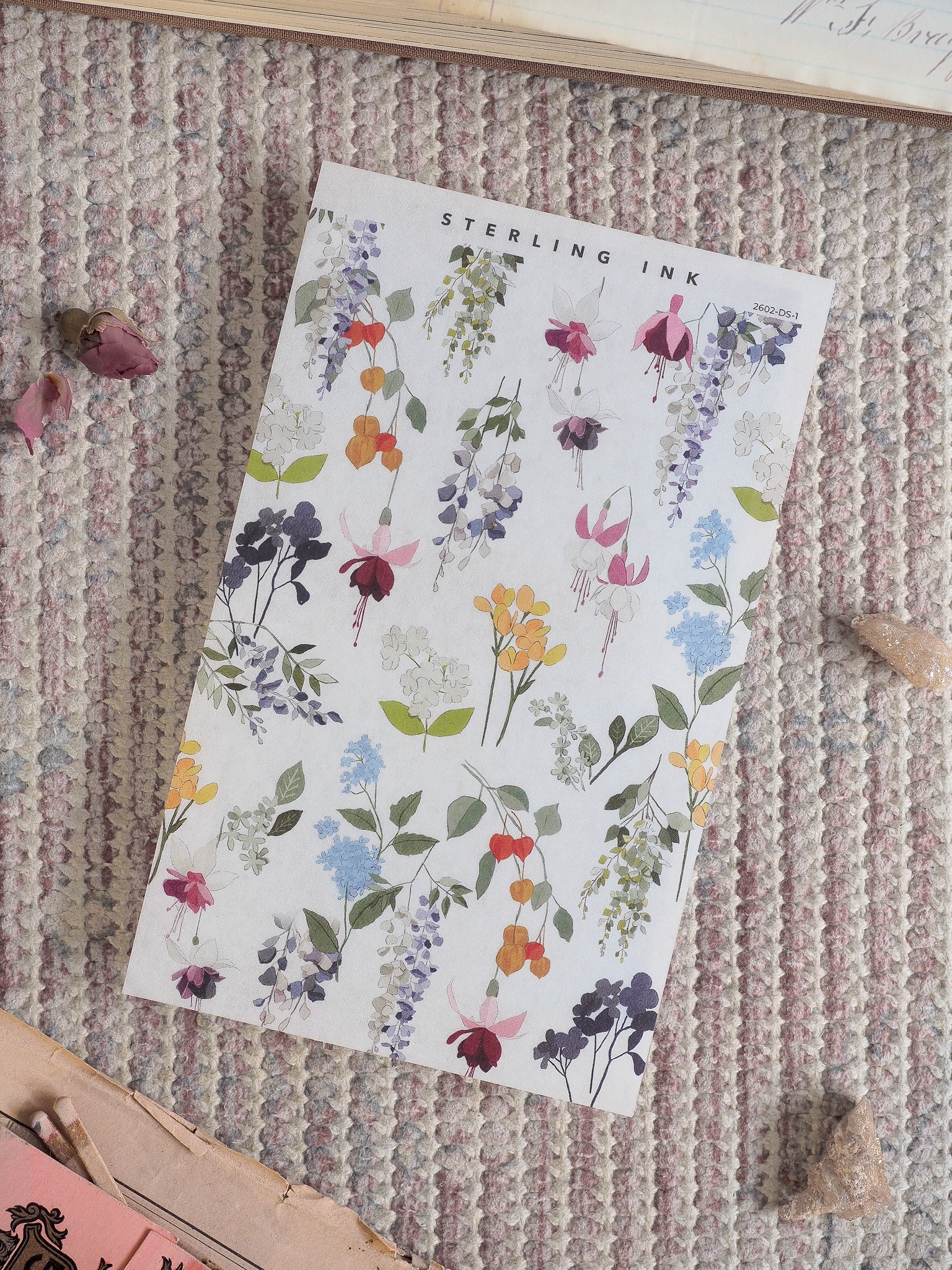 Decorative sheet featuring a delicate watercolor pattern of clustered spring flowers in pastel shades of pink, blue, yellow, and purple.