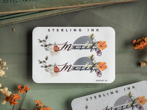 Elegant "March" month sticker featuring botanical watercolor blooms and greenery in warm autumn colors on a crisp white background.