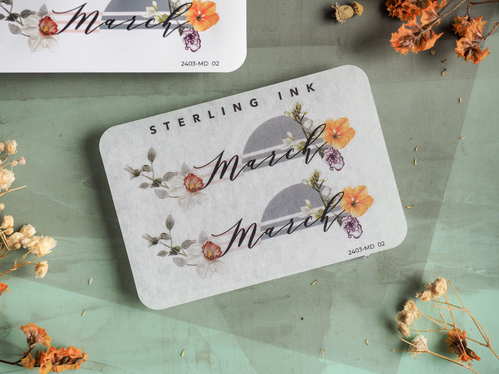 Pale gray planner sticker featuring the word March in delicate script, adorned with vibrant watercolor florals in soft shades of pink, orange, and purple.
