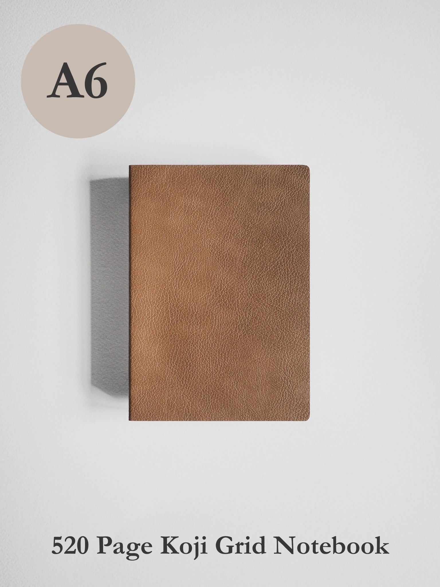 A6 size brown textured leather notebook cover shown closed on a light gray background, with text indicating it is a 520 page Koji Grid Notebook.
#Color_Caramel