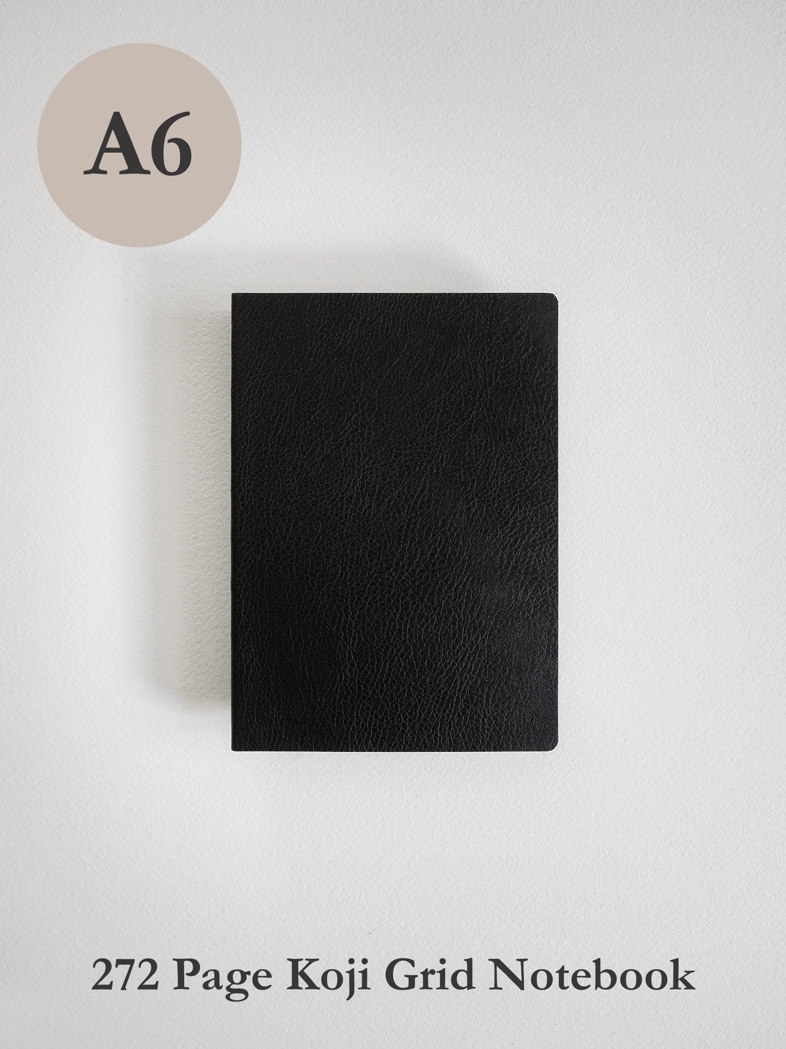 A black textured notebook shown from the front on a light gray background, with an A6 size circle label in the top left and the text '272 Page Koji Grid Notebook' at the bottom.
#Color_Onyx