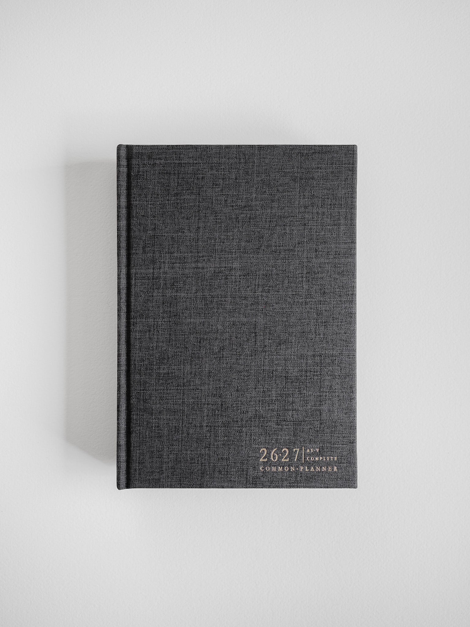 A structured A5 academic planner bound in dark grey, textured fabric, featuring the "Common Planner" title printed centrally on the front cover.