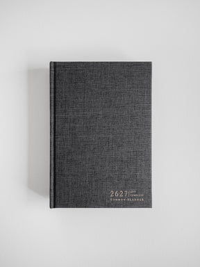 A structured A5 academic planner bound in dark grey, textured fabric, featuring the "Common Planner" title printed centrally on the front cover.