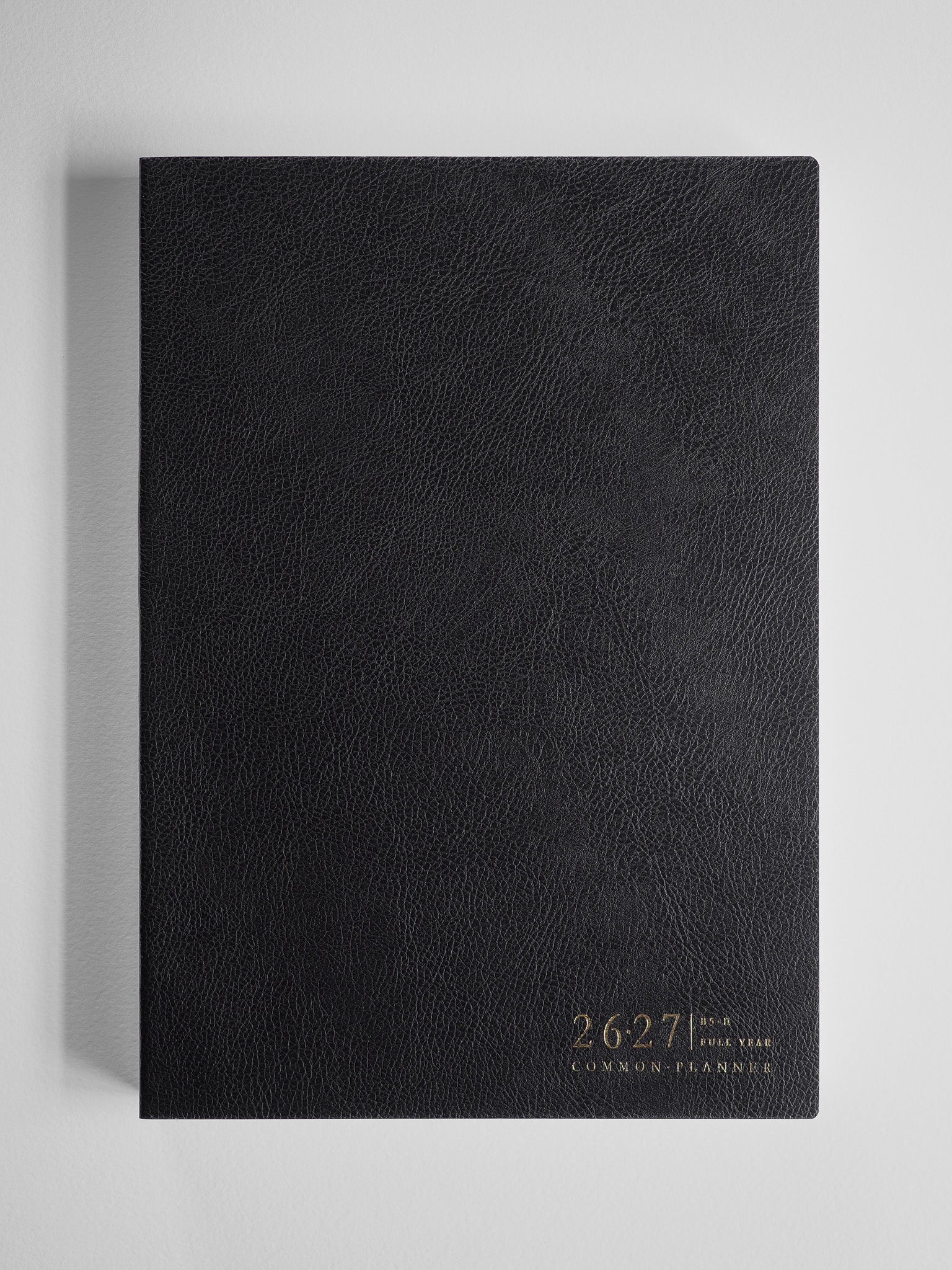 Black, academic B5 planner with a textured cover featuring the debossed years 26-27 and the text "Common Planner."