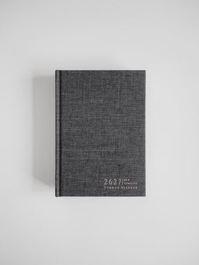 Dark charcoal B6 academic planner featuring a woven textured cover and minimalist white branding for the 2026-2027 Common Planner.