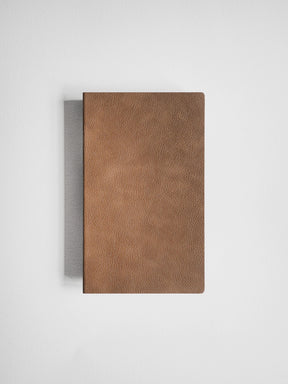 A brown textured leather notebook or journal with a visible gray spine, photographed from above on a clean white background.
#Color_Caramel