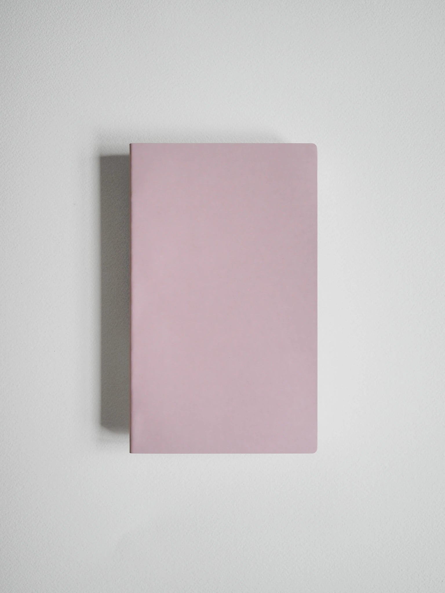 A minimalist, solid dusty pink hardcover notebook or journal shown from a top-down perspective on a light gray background.
#Color_Fairyfloss