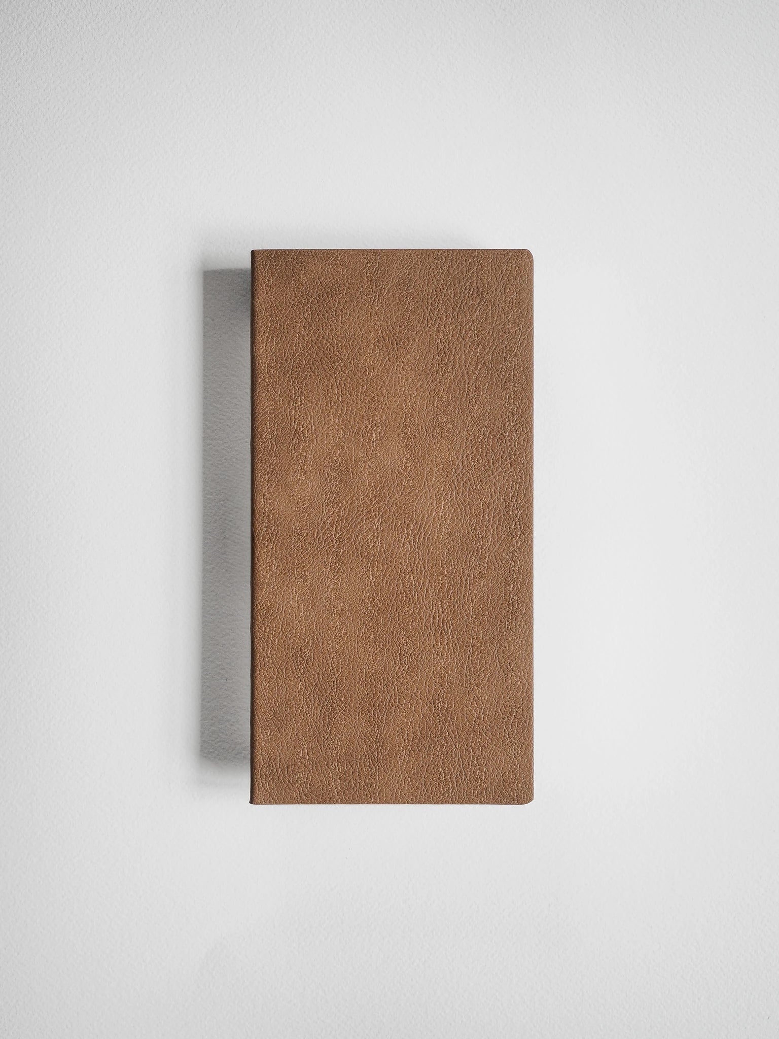 A brown textured leather or faux-leather rectangular case standing upright against a light gray background.
#Color_Caramel