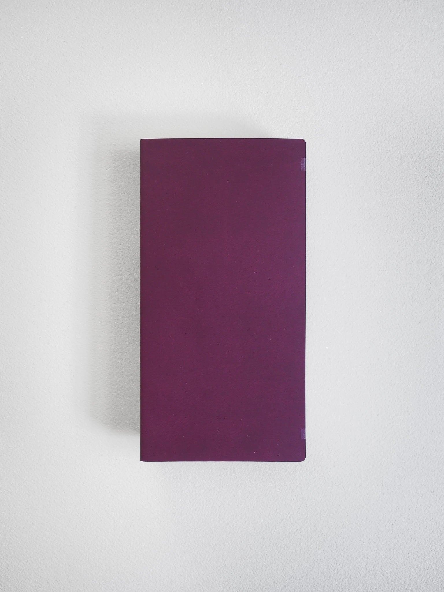 A rectangular dark purple book or notebook with a smooth matte cover, centered against a light gray textured background.
#Color_Mulberry