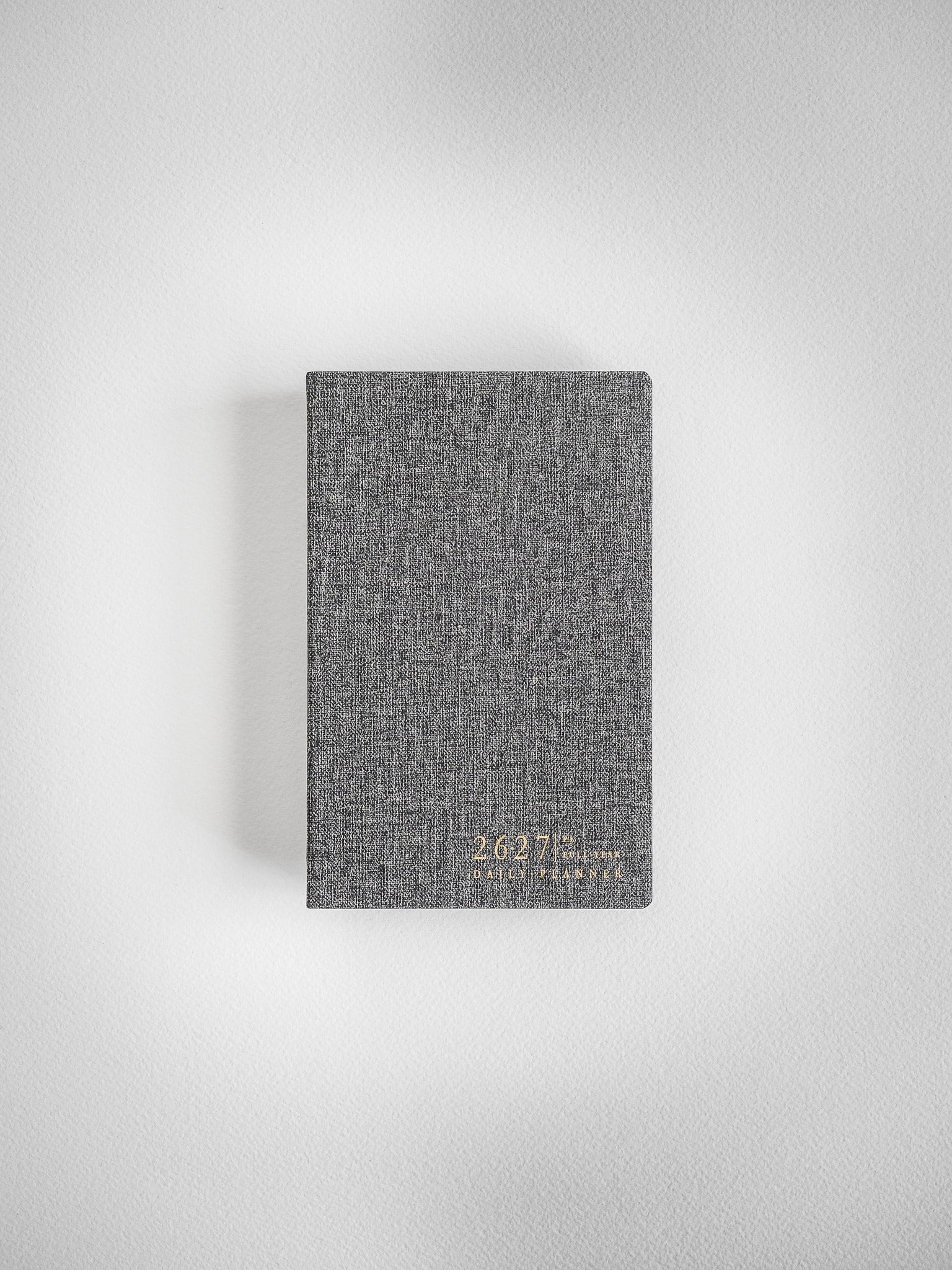 Compact academic daily planner featuring a dark gray, subtly textured, woven cover with visible branding details.