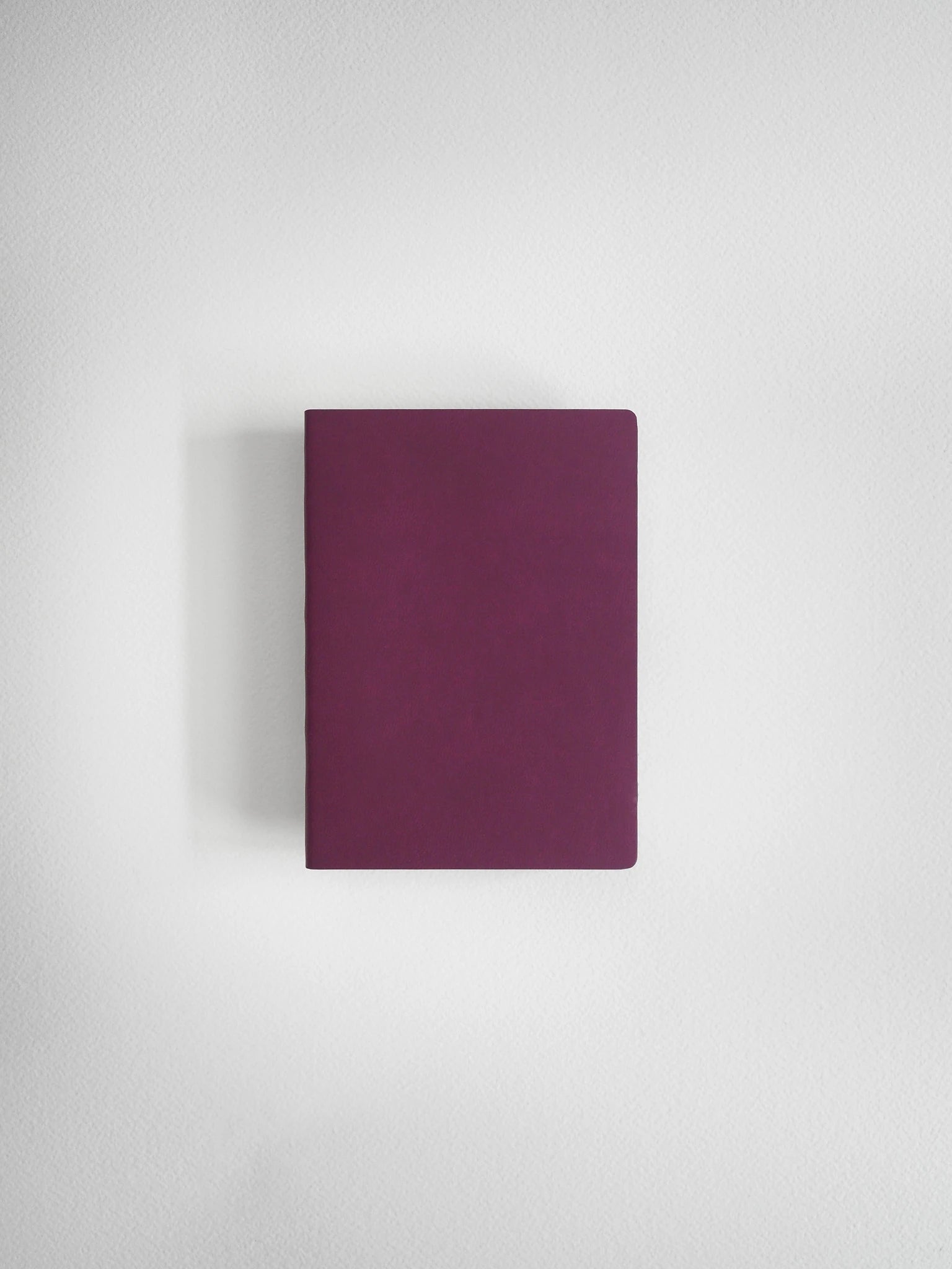 A minimalist, solid dark purple notebook or journal with rounded corners, centered against a clean, light gray textured background.
#Color_Mulberry
