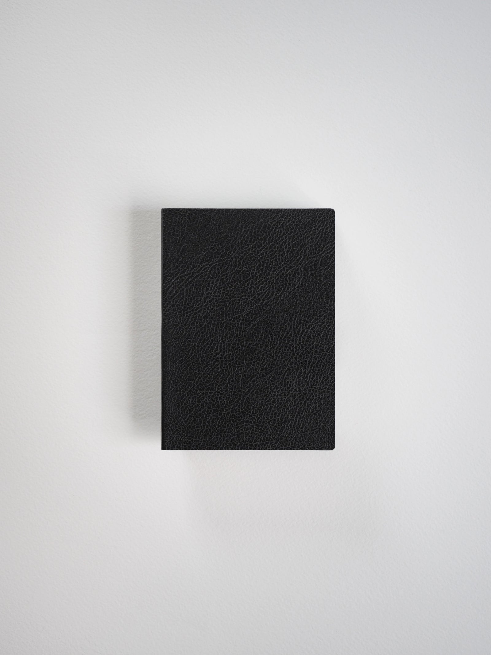 A black textured leather notebook or journal with a rectangular shape, shown from a top-down perspective on a light gray background.
#Color_Onyx