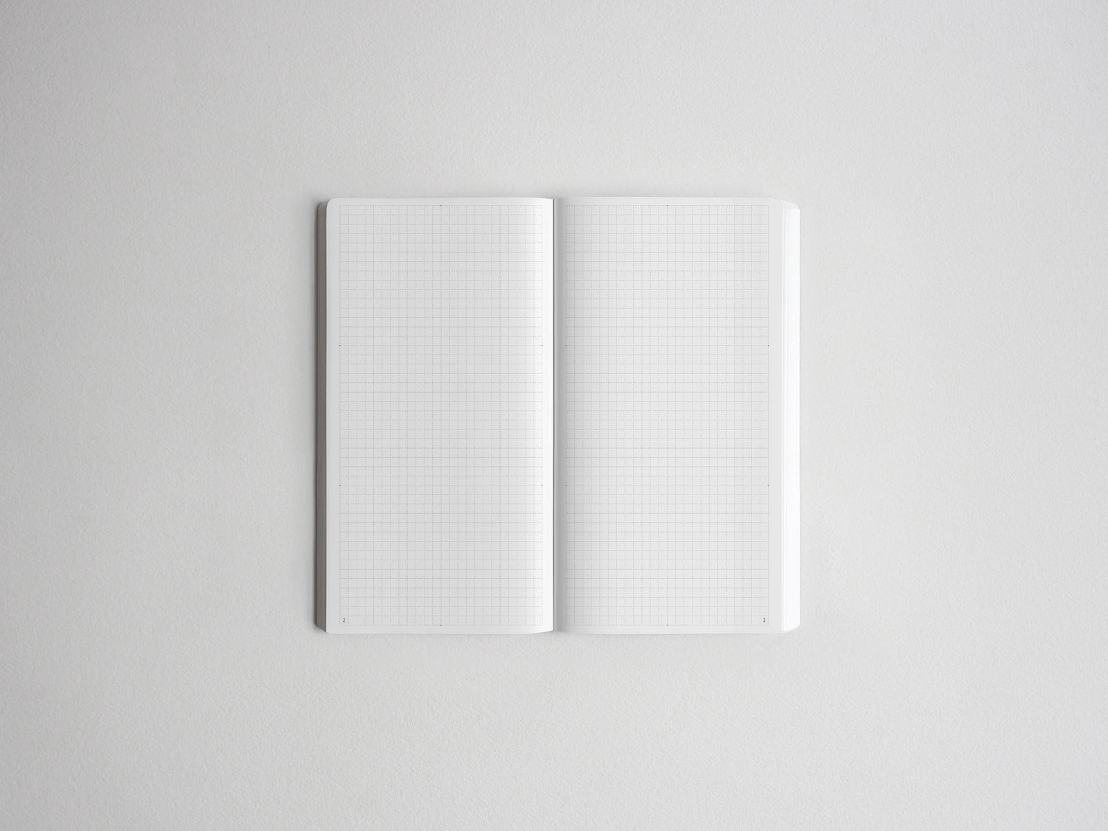 An open notebook with white grid paper pages, centered on a light gray background.