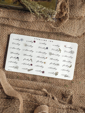 Planner sticker sheet displaying repeating weekday labels and delicate floral accents in blush and burgundy, perfect for organizing a themed journal or bullet journal.