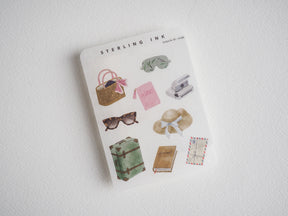 Vintage travel sticker collection: luggage, passport, sunglasses, sun hat, camera, journal, and stationery items for