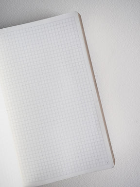 Open B6 grid notebook featuring neat, light graph paper lines across crisp white pages, perfect for detailed journaling and academic notes.