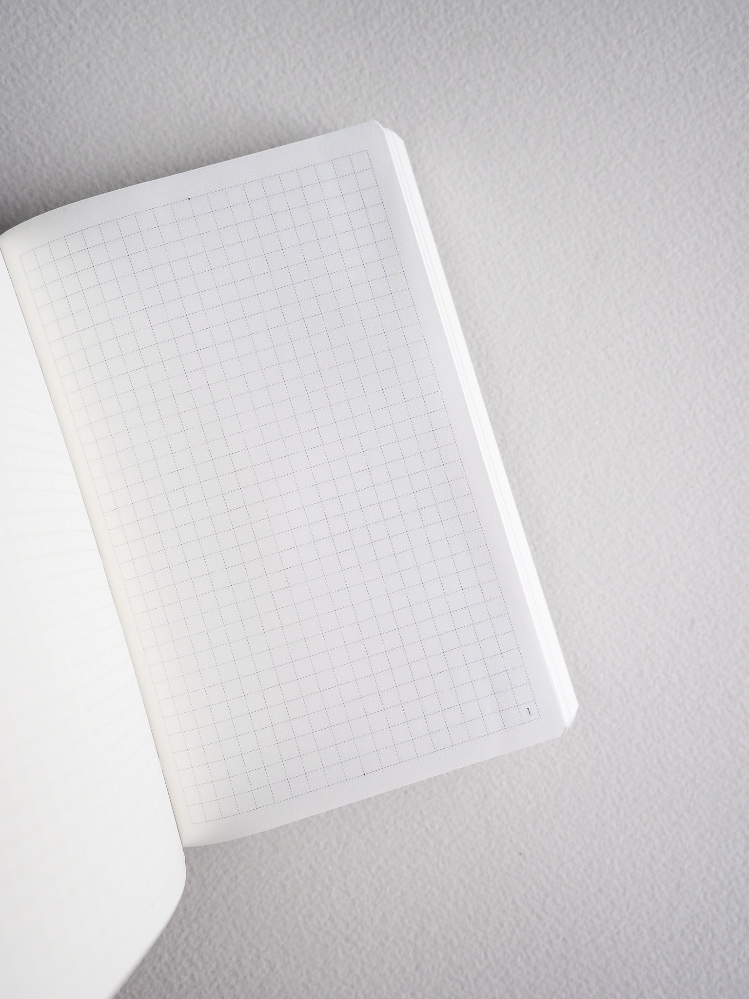 Compact white notebook featuring fine, uniform grid lines on the pages, ideal for structured pocket planning and note-taking.