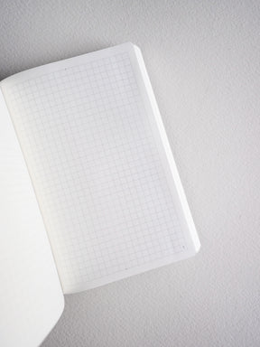Compact white notebook featuring fine, uniform grid lines on the pages, ideal for structured pocket planning and note-taking.