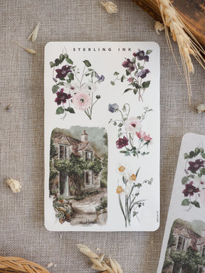 Spring arrangement stickers featuring delicate watercolor bouquets of purples and blush pinks, alongside a picturesque illustration of a mossy, rustic stone cottage.