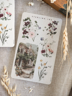 Delicate sticker sheet featuring watercolor spring florals and bouquets arranged alongside a charming, detailed sketch of an English cottage.