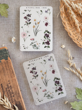 Watercolor botanical sticker sheets featuring delicate clusters of purple, pink, and cream wildflowers with a rustic, earthy aesthetic.