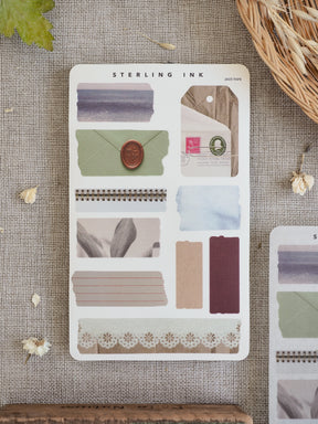 Various torn tape stickers in dusty blue, beige, and cream tones, including solid strips and delicate patterned washi designs for journal scrapbooking.