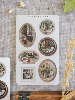 Vintage sepia-toned picture frame stickers featuring architectural sketches of rustic houses, charming gardens, and historical scenes from the March 2026 collection.