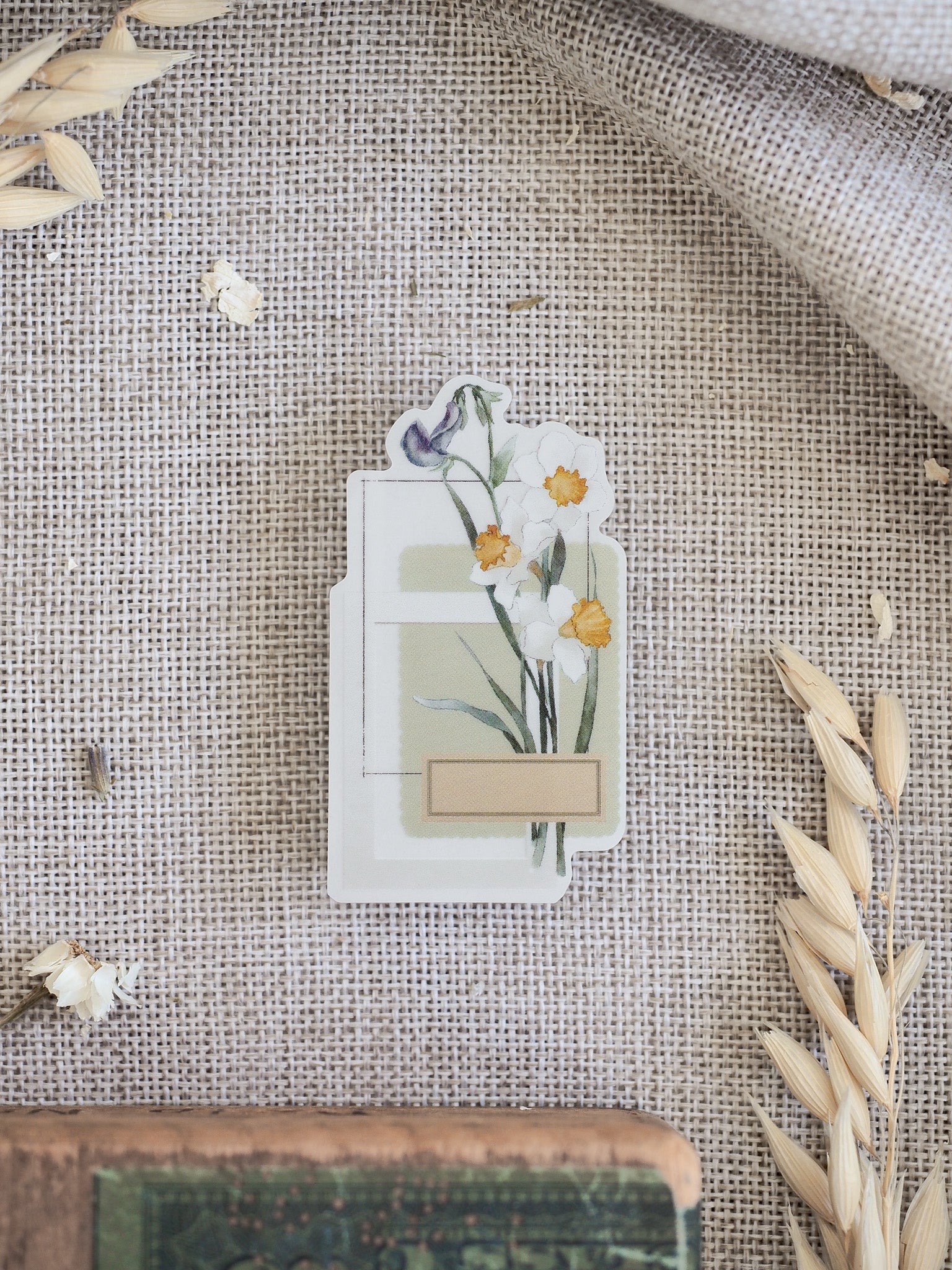 Pastel spring floral die-cut sticker featuring delicate white and yellow blossoms with green foliage, and an integrated banner for labeling or planning.
