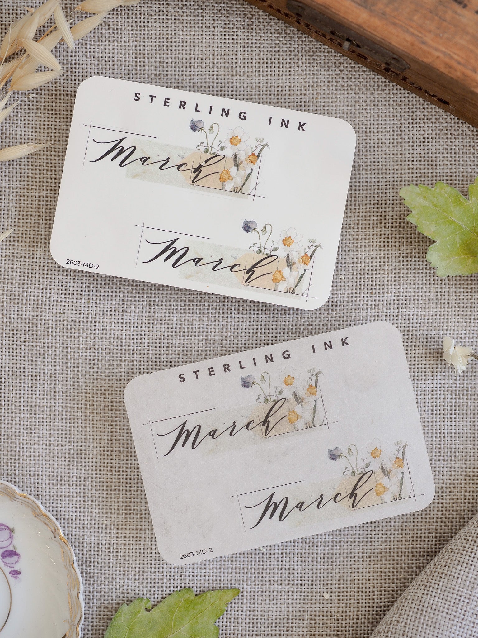 Spring-themed March month sticker featuring "Sterling Ink" and delicate watercolor floral illustrations in shades of yellow and green.