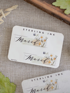Decorative March sticker featuring "Sterling Ink" branding, elegant script, and soft watercolor illustrations of yellow and purple wildflowers.