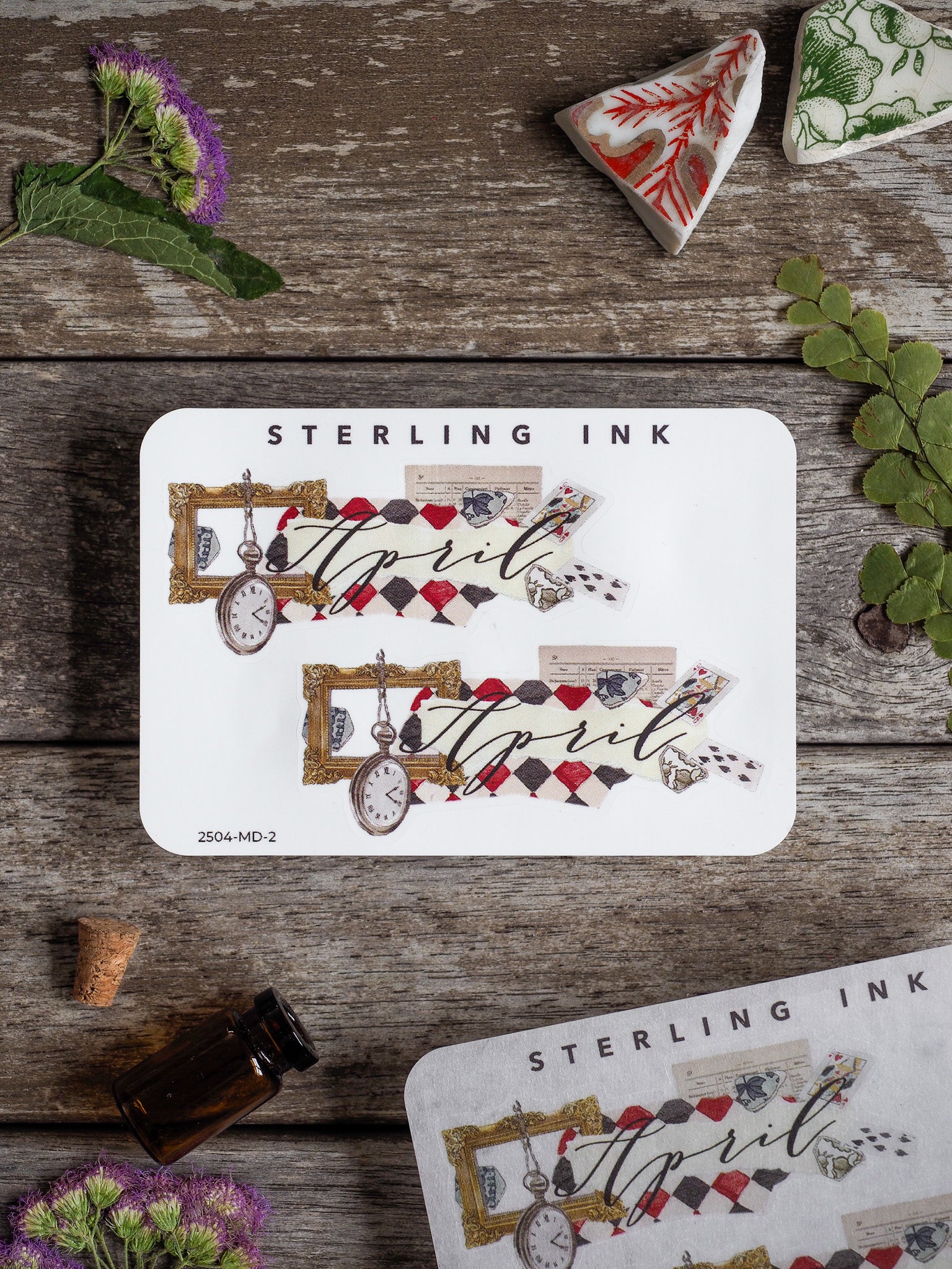 Elegant April monthly sticker featuring cursive script, vintage pocket watch motifs, and decorated frames in muted red, cream, and gold tones.