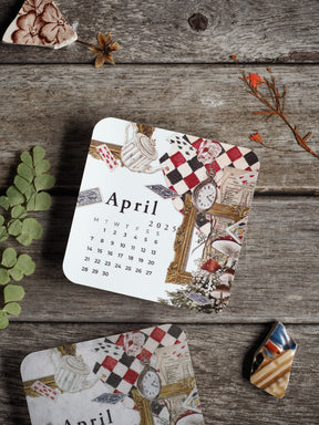 A decorative April 2025 monthly calendar featuring a distressed, vintage pattern of teacups, antique clocks, and ornate graphic elements.