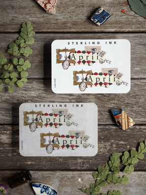 Ornate April month sticker featuring a vintage, scrapbook aesthetic with decorative clock elements, patterned accents, and a classic red and gold color scheme.