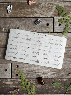 Elegant weekly sticker sheet for April 2025 featuring delicate, scattered script calligraphy words printed in deep ink on creamy, vintage-style cardstock.