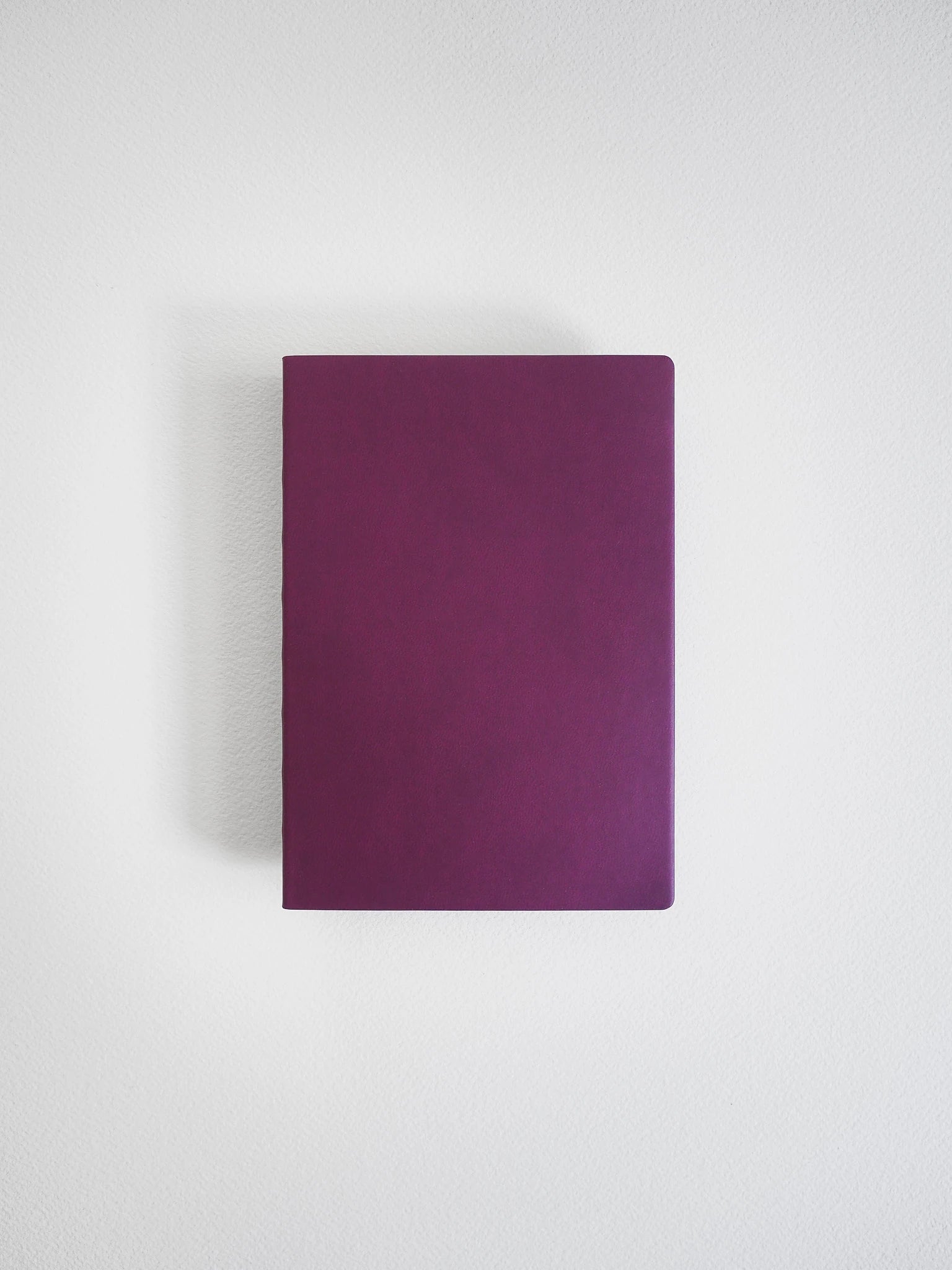 A minimalist, solid deep purple notebook or journal with a matte finish, shown from a top-down perspective against a clean, light gray background.
#Color_Mulberry