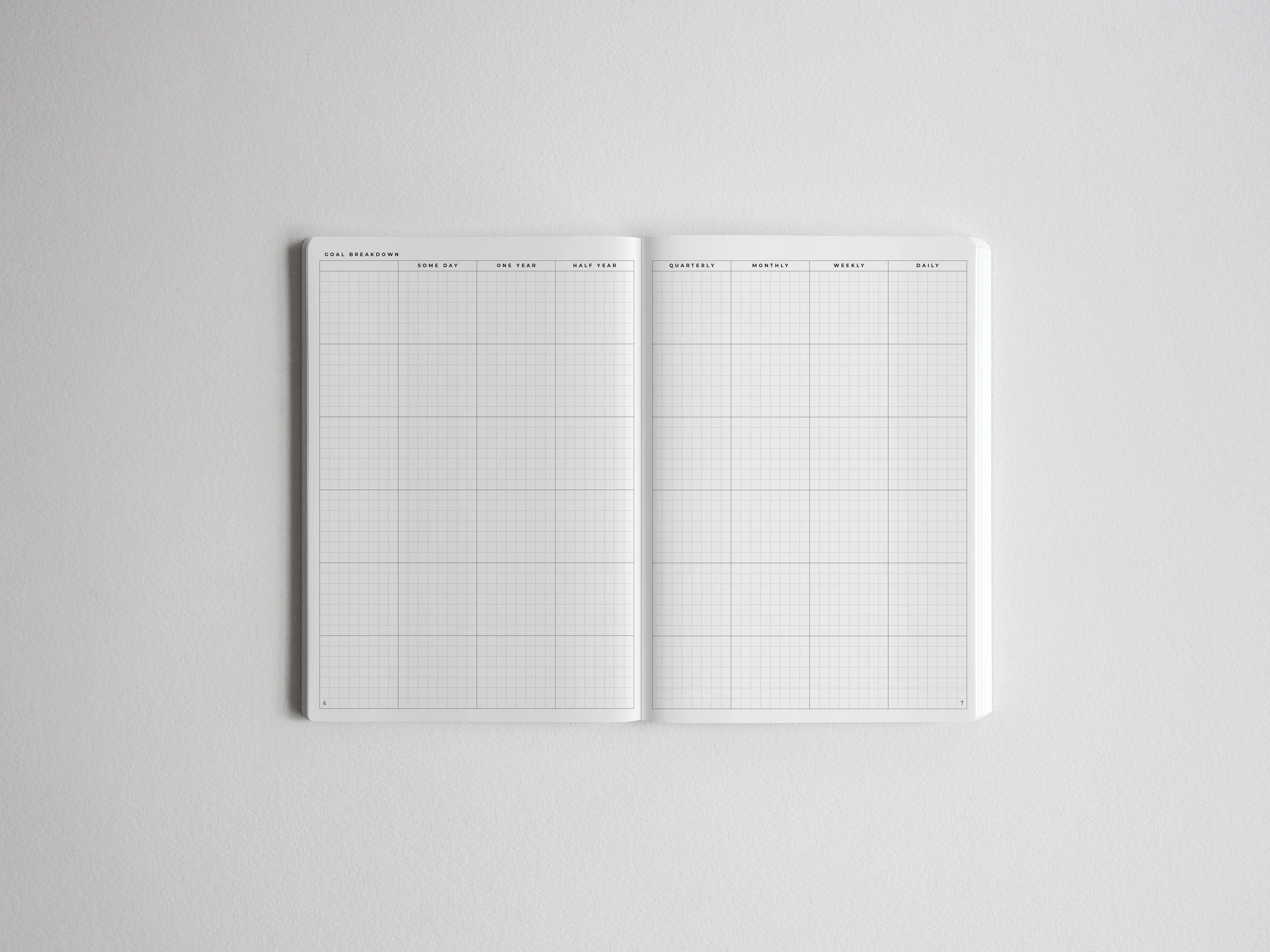 Open planner spread detailing goal breakdown, with structured grids for yearly, quarterly, monthly, weekly, and daily planning and tracking.