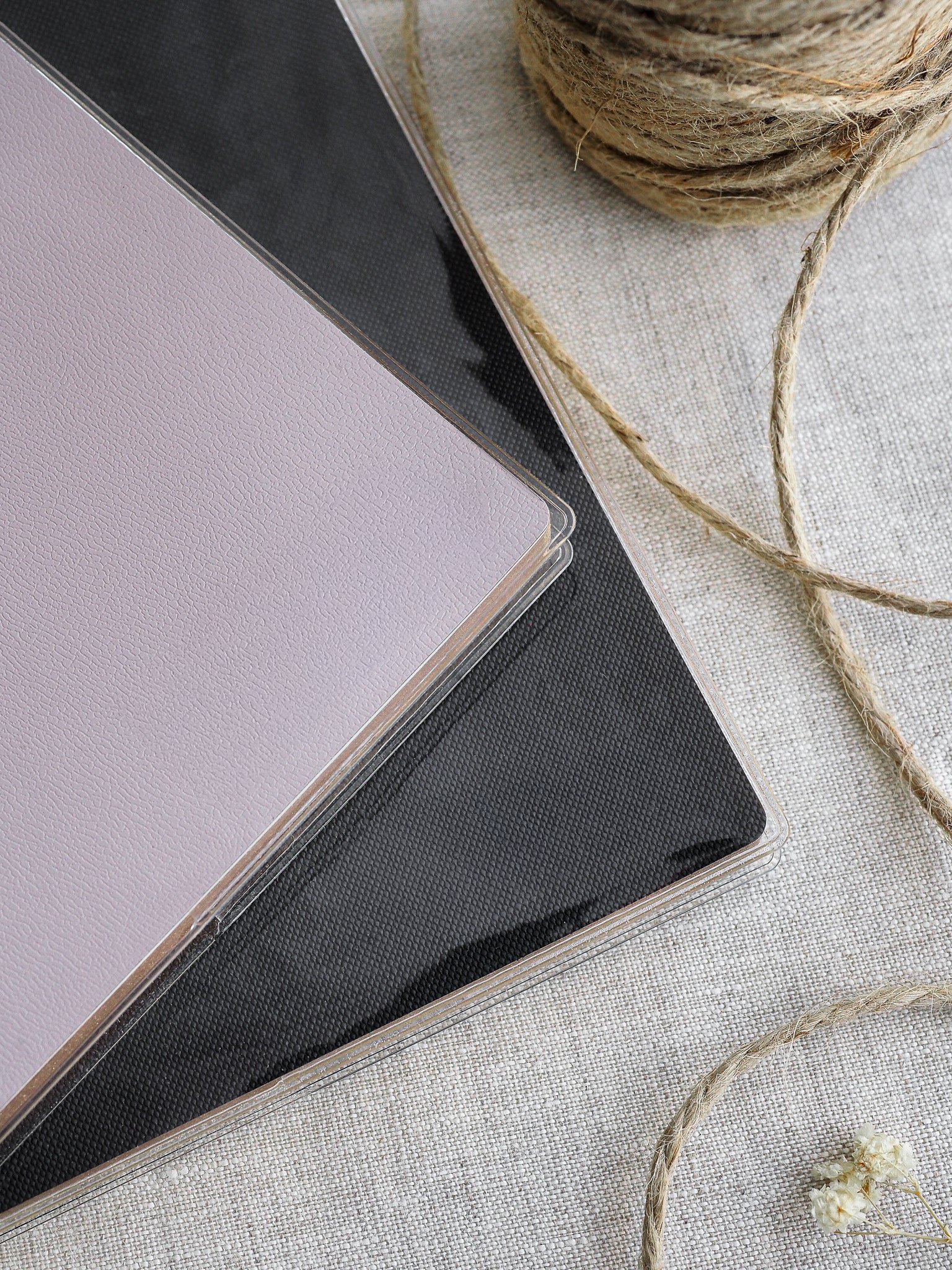 Clear protective sleeves for journals and planners, showcasing clear material over underlying solid colors of light beige and deep charcoal gray.