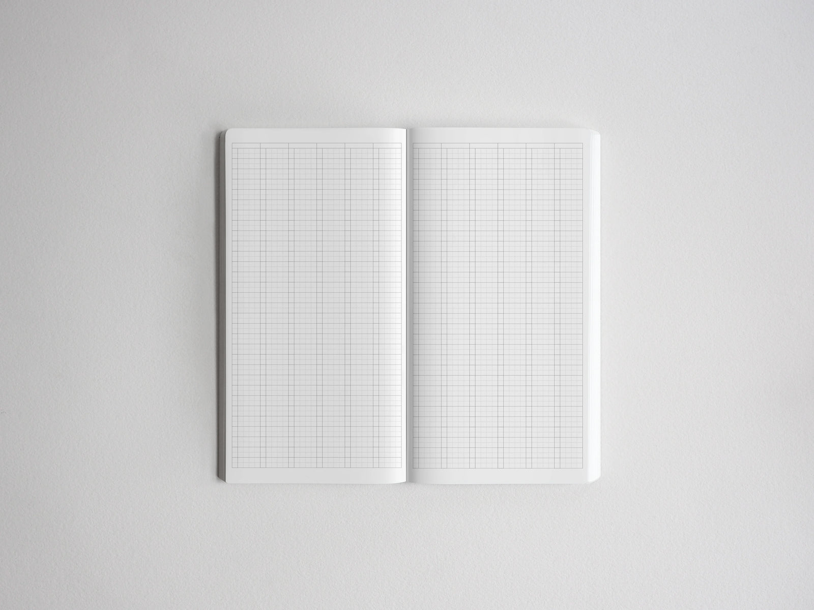 Open notebook showcasing two blank, white pages ruled with precise graph paper grids for sketching, planning, or detailed note-taking.