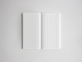 Open notebook showcasing two blank, white pages ruled with precise graph paper grids for sketching, planning, or detailed note-taking.