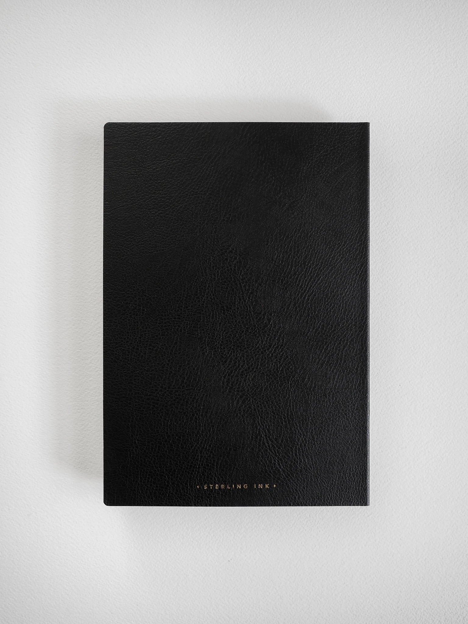 A black textured notebook or journal with 'STERLING INK' printed in small gold lettering at the bottom, shown flat against a light gray background.
#Color_Onyx