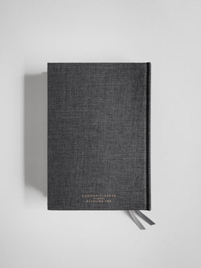Dark charcoal A5 academic planner with a fabric cover, branded with "Common Planner," and featuring a decorative ribbon closure for organization.