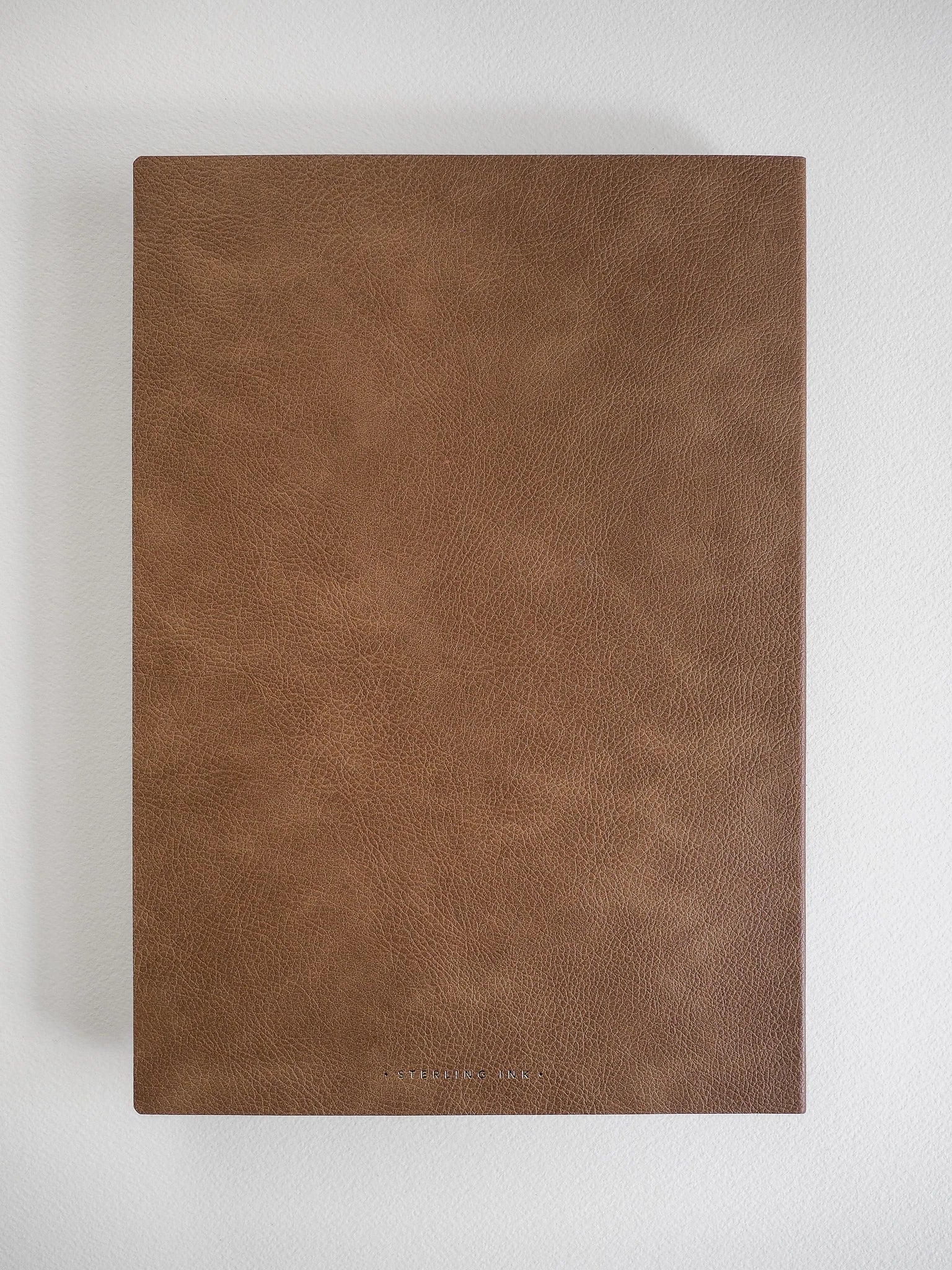 A brown textured faux-leather notebook or journal cover shown flat against a light gray background.
#Color_Caramel