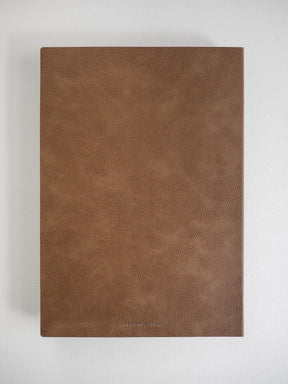 A brown textured faux-leather notebook or journal cover shown flat against a light gray background.
#Color_Caramel