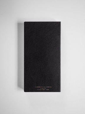 Black academic planner with a sophisticated, textured cover debossed with metallic gold lettering reading "COMMON PLANNER" and "Designed by STEMLING INK."
