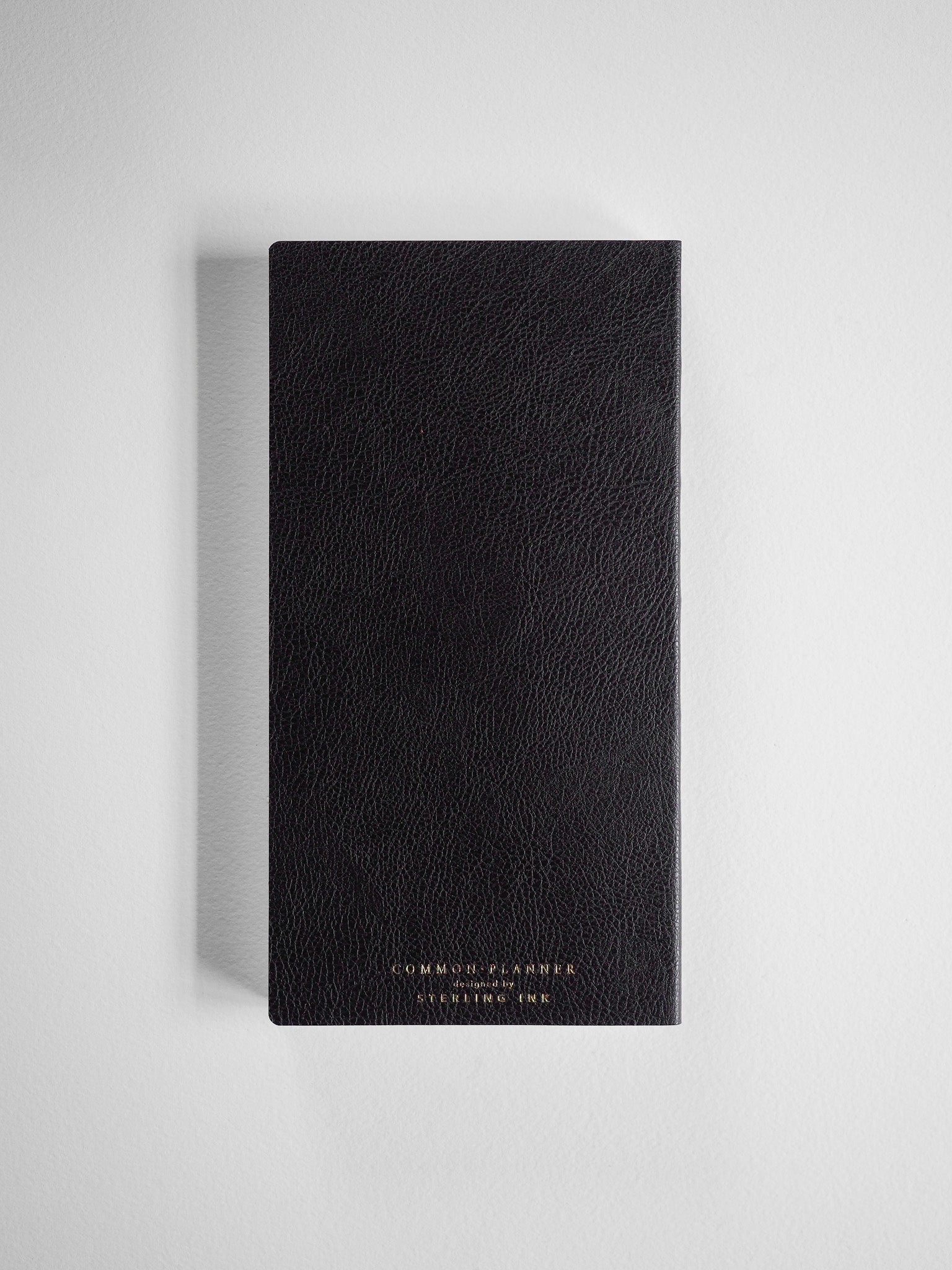 A textured, vertical black planner featuring debossed gold lettering that reads "COMMON PLANNER" and "STEMLING INK," ready for academic year planning.