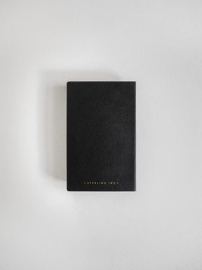 A black textured leather notebook or journal with gold foil 'STERLING INK.' branding at the bottom, shown flat on a light gray background.
#Color_Onyx
